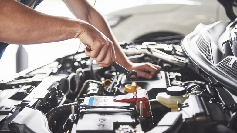 Especialista realizando un mantenimiento preventivo a al motor de un auto.