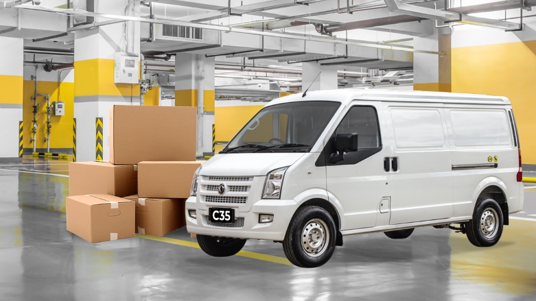 Van de carga DFSK C35 color blanca estacionada al lado de cajas con mercancía.